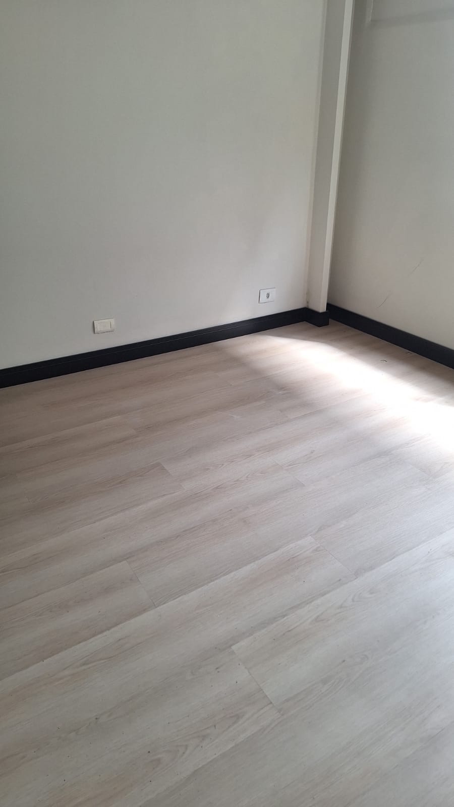 Piso amadeirado claro com rodapé escuro em ambiente vazio